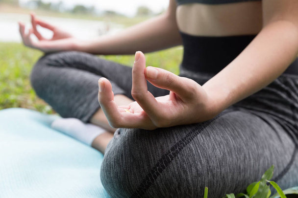 Młoda kobieta medytuje podczas uprawiania jogi odkryty w parku, re - Zdjęcie, obraz