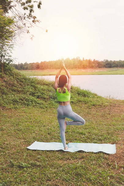 Nuori nainen harjoittelee jooga harjoituksia ulkona puistossa, rentoutua
 - Valokuva, kuva