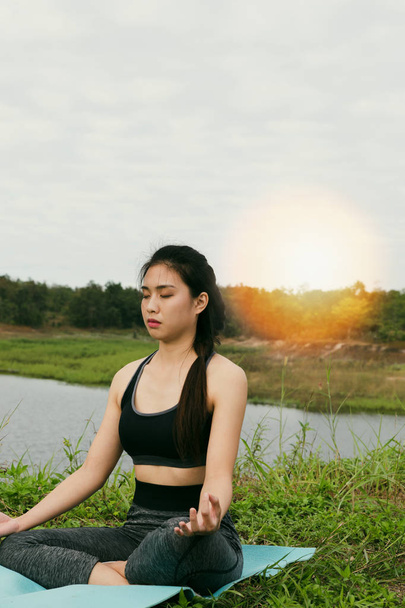Młoda kobieta medytuje podczas uprawiania jogi odkryty w parku, re - Zdjęcie, obraz