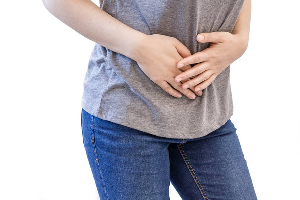 Young woman with stomach issues. woman white sport shirt stomachache and hand at abdomen. menstruation pain or stomach ache, hand holding belly closeup - Foto, Imagen