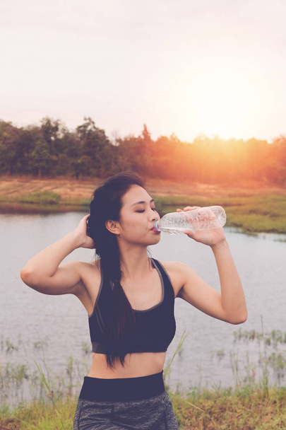 Sport und gesunder Lebensstil - junge Frau trinkt Wasser aus einem B - Foto, Bild