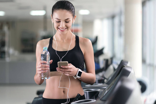 Athletic girl using smartphone in a gym - Fotoğraf, Görsel
