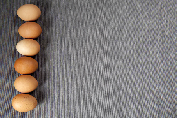 έξι αυγά βρίσκονται στη γραμμή στην άκρη του γκρι χαρτοπετσέτας.  - Φωτογραφία, εικόνα