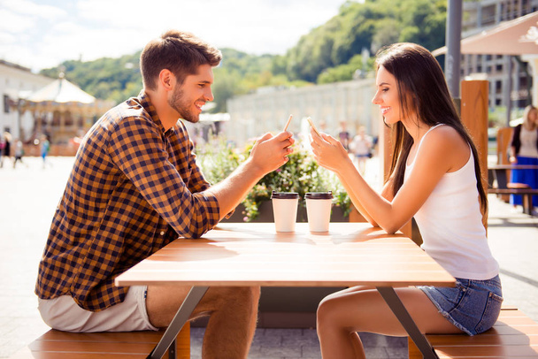 Due amanti che hanno appuntamento in caffè e digitando sms su smartphone
 - Foto, immagini