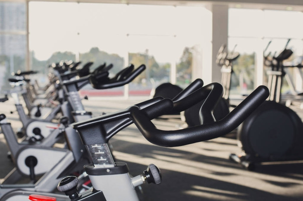 Modern gym interior with equipment, fitness exercise bikes handlebars - Photo, Image