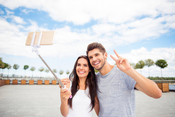 Smiling attractive man and woman making selfie on monopod - Фото, изображение
