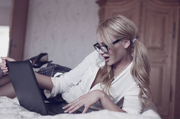 Sexy femme blonde intelligente chat sur ordinateur portable au lit
 - Photo, image
