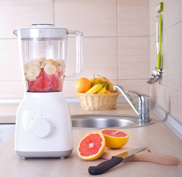 Blender with sliced grapefruit on kitchen countertop - Photo, Image