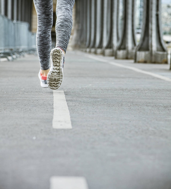 Closeup on woman jogger running on Pont de Bir-Hakeim bridge - Foto, Imagem