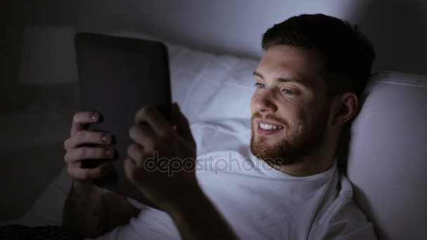young man with tablet pc in bed at home bedroom - Záběry, video