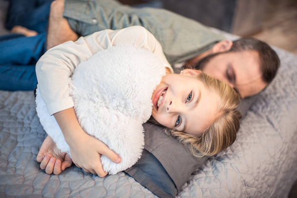 Father and daughter lying on bed - Фото, изображение