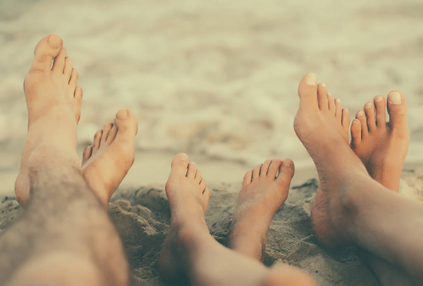 Drie paren van voeten op het zand. Familie op vakantie. - Foto, afbeelding