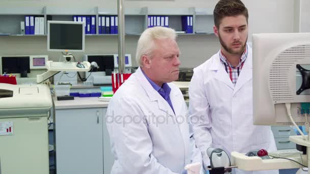Dos hombres miran el monitor del laboratorio.
 - Metraje, vídeo