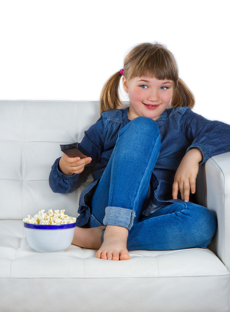 Girl sitting on a couch watching TV - Photo, Image