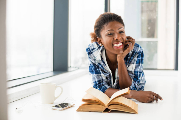 fekete nő olvasó egy könyv mellett egy nagy ablak-val természetes lig - Fotó, kép
