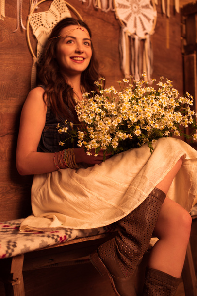 bohemian woman sitting with bouquet of chamomiles - Фото, изображение