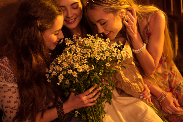 women in boho style smelling flowers - Фото, изображение