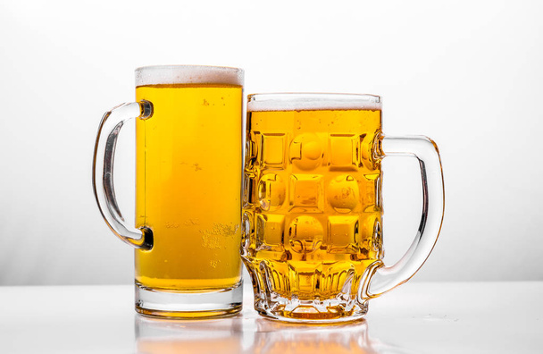 Two Mugs of fresh beer with cap foam - Photo, image
