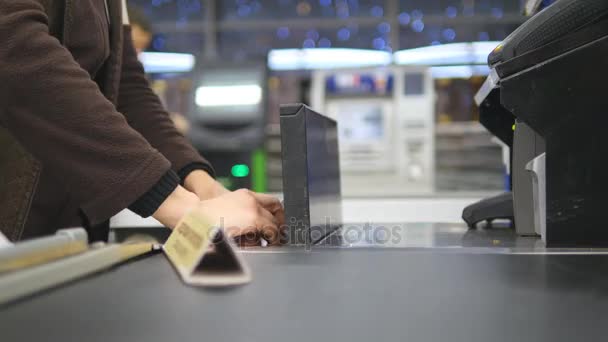 Shopper paying for products at checkout. Foods on conveyor belt at the supermarket. Cash desk with cashier and terminal in hypermarket. Working of cashier. Shopping at store. Close up - Footage, Video