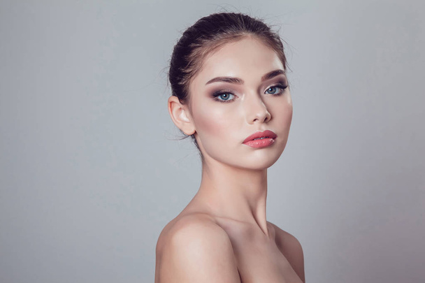 Beautiful brunette girl with makeup on grey background, youth and skin care concept. - Valokuva, kuva
