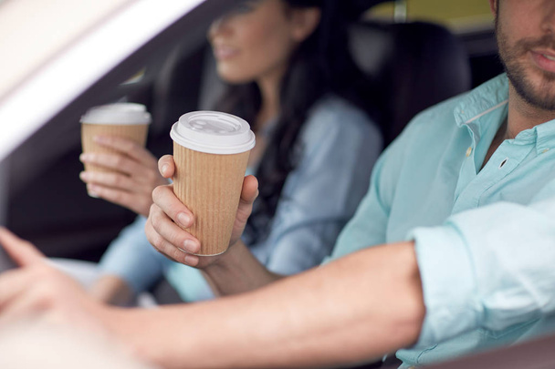 close up of couple driving in car with coffee cups - Foto, immagini