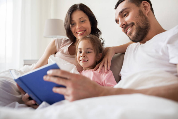 happy family reading book in bed at home - Фото, зображення