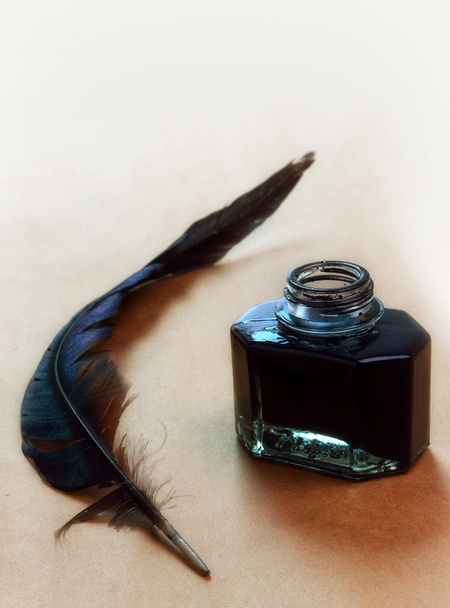 Feather and ink bottle on brown paper - Foto, imagen