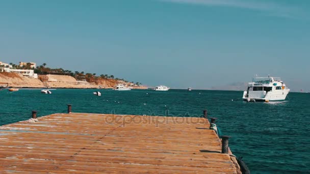 Zeegezicht met houten pier tegen de achtergrond van witte jacht drijft - Video