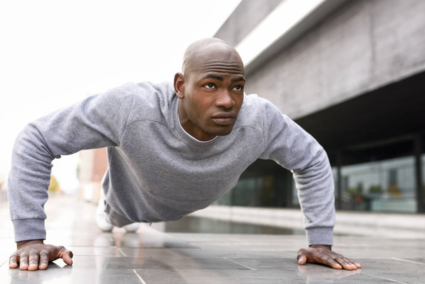 Fitness zwarte man uitoefening push-ups op stedelijke achtergrond - Foto, afbeelding