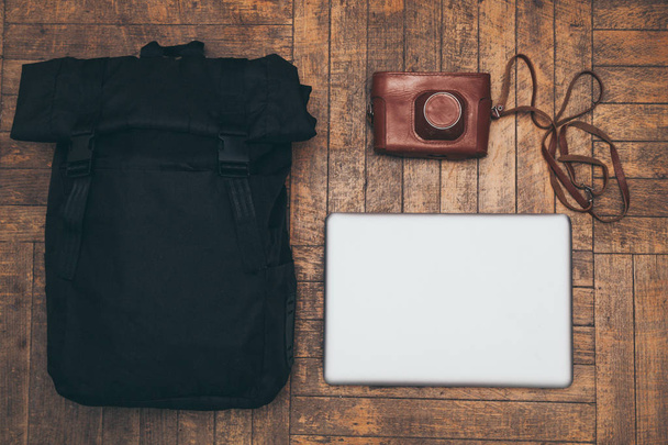 Film camera in the bag, the bag, and a laptop on a wooden background. - 写真・画像