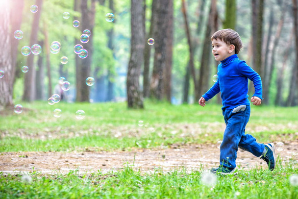 Little boy with soap bubbles in summer park. - Foto, Imagen