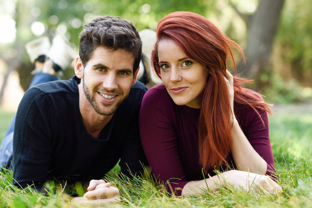 Schönes junges Paar liegt auf Gras in einem Stadtpark.  - Foto, Bild