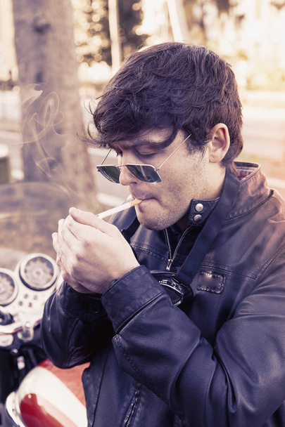 young biker relaxing smoking a cigarette - Foto, Bild
