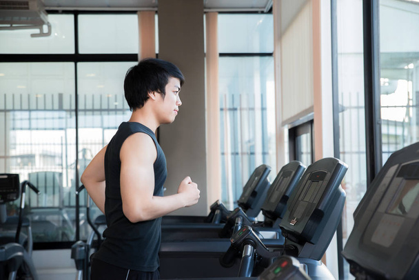 Ασιατικές νεαρός άνδρας τρέχει στο διάδρομο στο γυμναστήριο. Υγείας και αθλητισμού co - Φωτογραφία, εικόνα