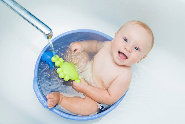 Happy baby boy taking a bath in hand wash basin - 写真・画像