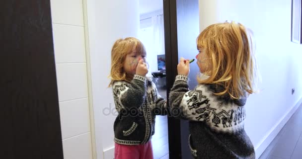 happy child painting her face looking at mirror - Footage, Video