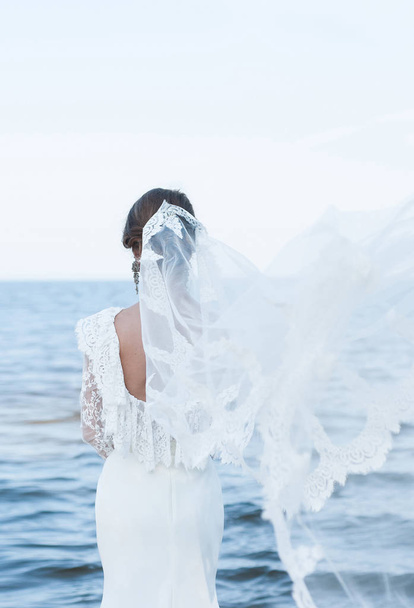 The bride in a beautiful dress and vintage faie looking at the sea.  - Foto, Imagen