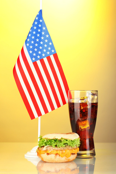 tasty sandwich and cola with american flag, on yellow background - Фото, изображение