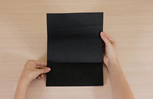 Hands holding blank black brochure booklet in the hand. Leaflet  - Photo, image