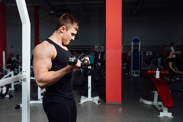 Portrait of a muscular young man lifting weights on gym - Foto, Imagen