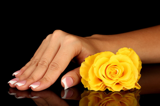 Yellow rose with woman's hand on black background - Zdjęcie, obraz