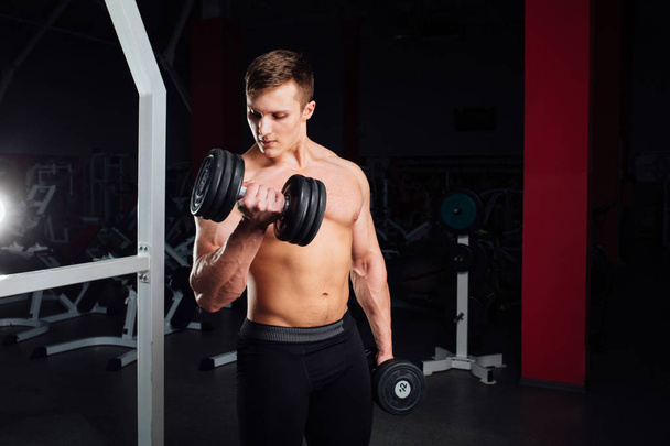 Closeup portrait of professional bodybuilder Strong muscular yang man doing exercise. Workout with barbell at gym.  Sports and fitness. Training  guy pumping up hands biceps. - 写真・画像