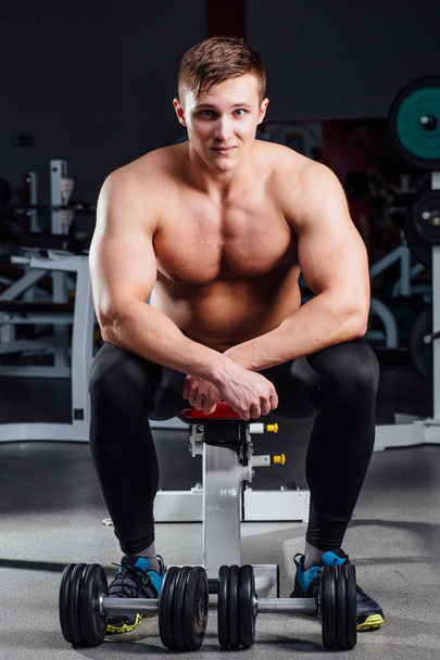 professional bodybuilder sitting on the bench, resting between exercises with dumbbells at gym. Big - Foto, Imagem