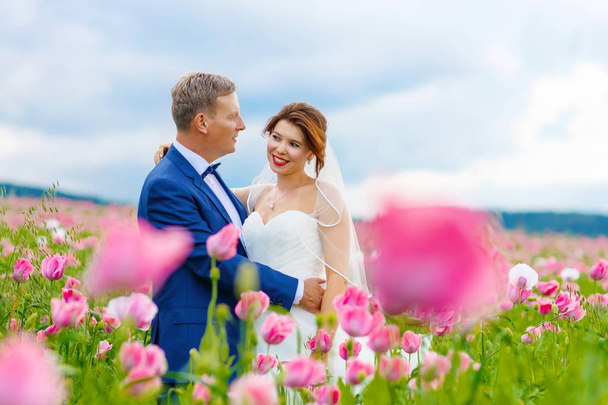 Щаслива весільна пара в рожевому маковому полі
 - Фото, зображення