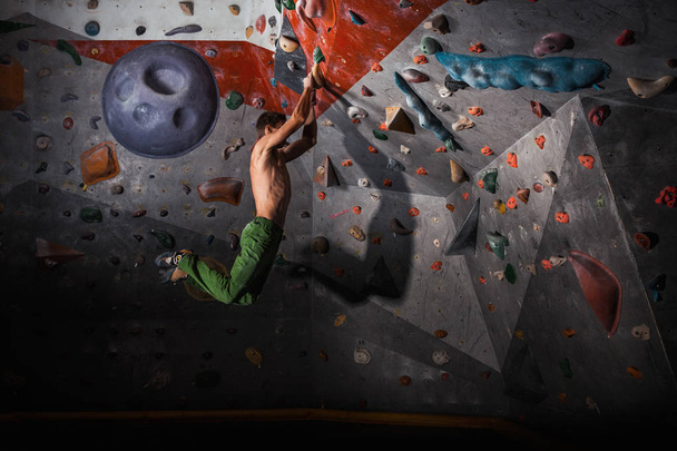 hombre practicando escalada en roca en una pared de roca en el interior
 - Foto, Imagen
