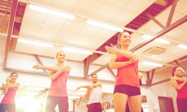 group of smiling people stretching in the gym - Valokuva, kuva
