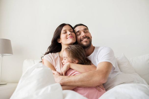happy family hugging in bed at home - Foto, afbeelding