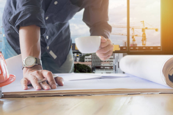 Image of engineer holding a cup of coffee and check blue print - Photo, Image