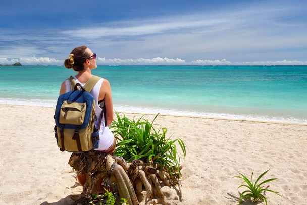 熱帯のビーチの美しい景色を楽しみながらのバックパックと幸せな若い女 - 写真・画像