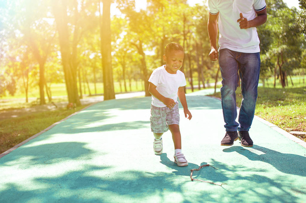 afroamericano ragazzo a piedi e giocare con papà in verde parco all'aperto
. - Foto, immagini